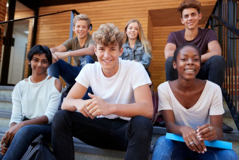 Group of teenagers sitting on steps and smiling