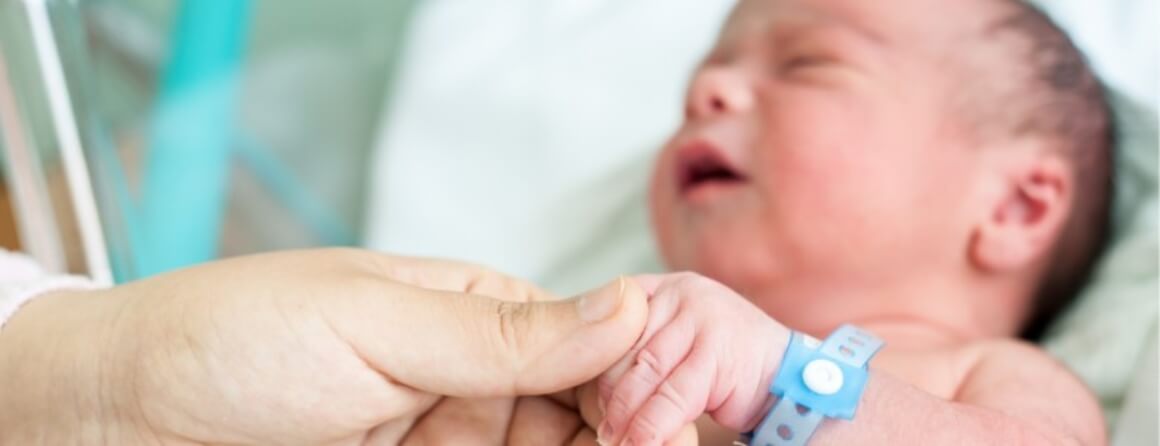 Person holding the left hand of a newborn infant