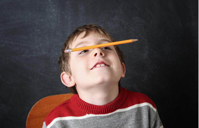 child balancing pencil on nose