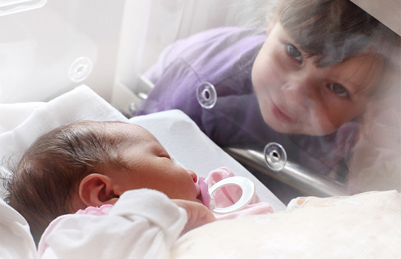 Girl watching over baby in hospital