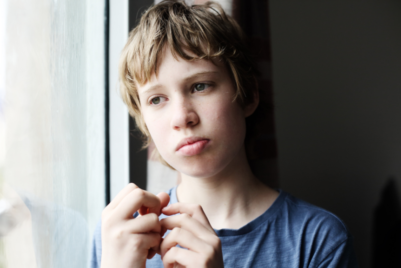 Pensive boy with autism looking out the window