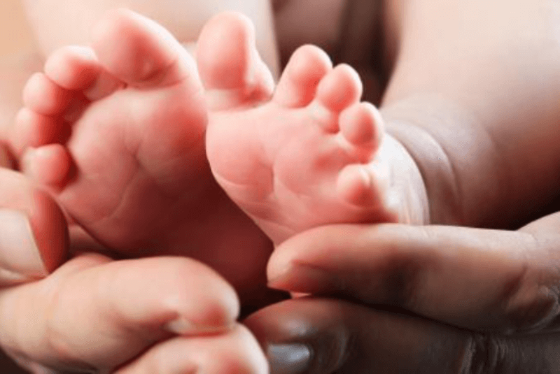 Woman's hands cradling an infant's feet