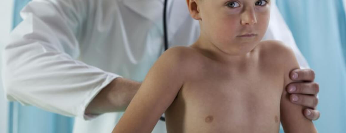 Doctor examining young boy's chest using a stethoscope