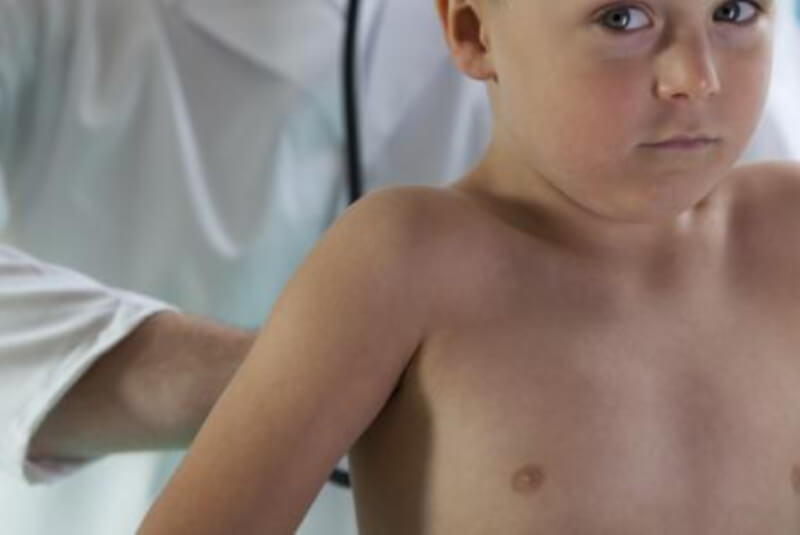 Doctor examining young boy's chest using a stethoscope