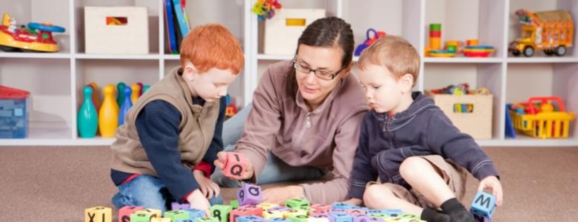 Woman with two boys working with letter and number blocks