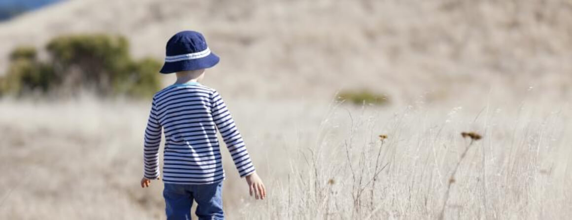Young child walking through tall grass