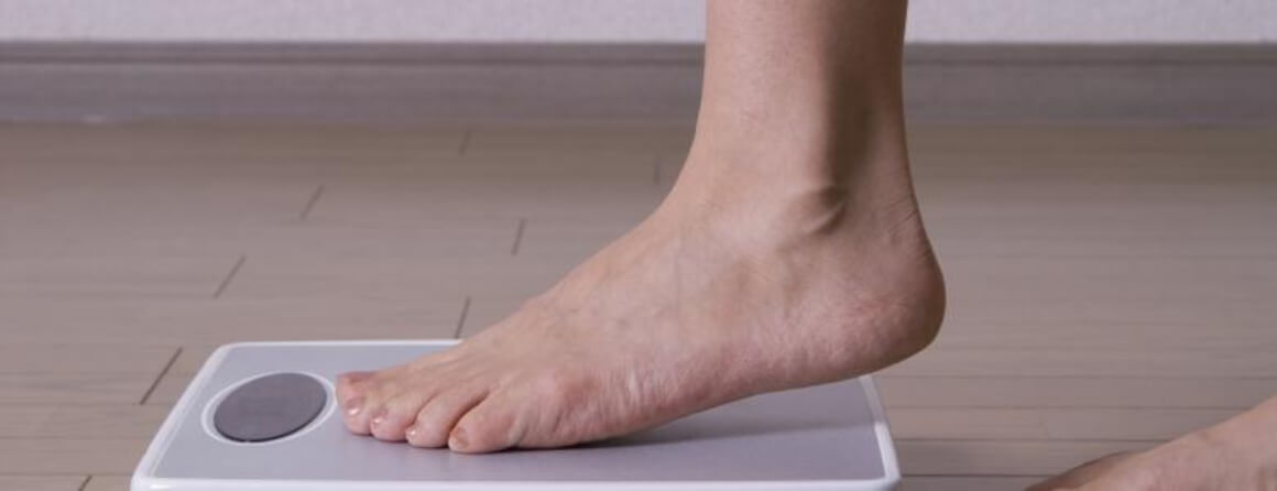 Adult foot stepping onto a bathroom scale