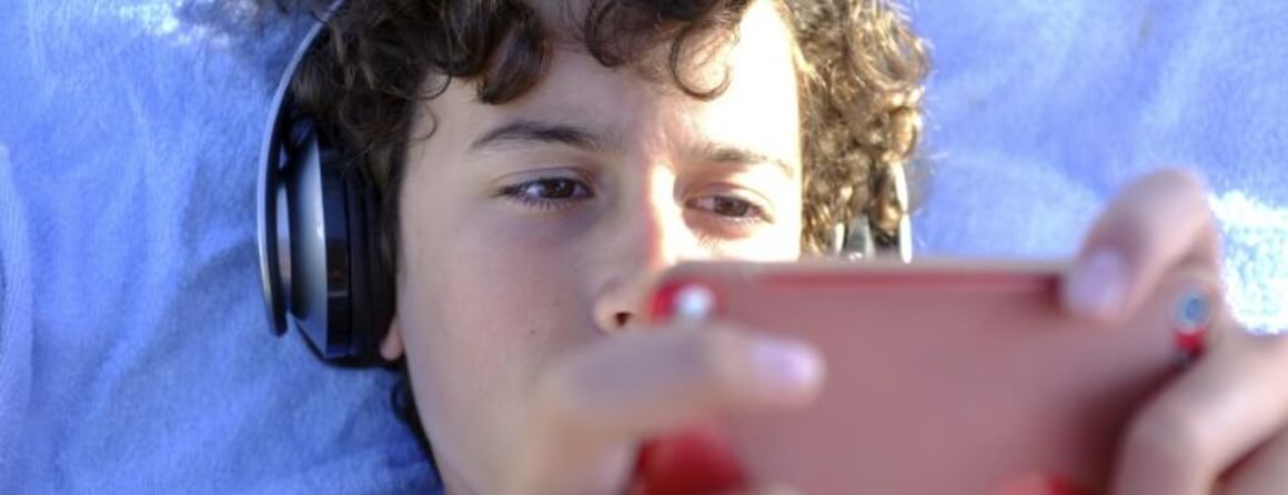 Teenage boy wearing headphones and using a mobile device
