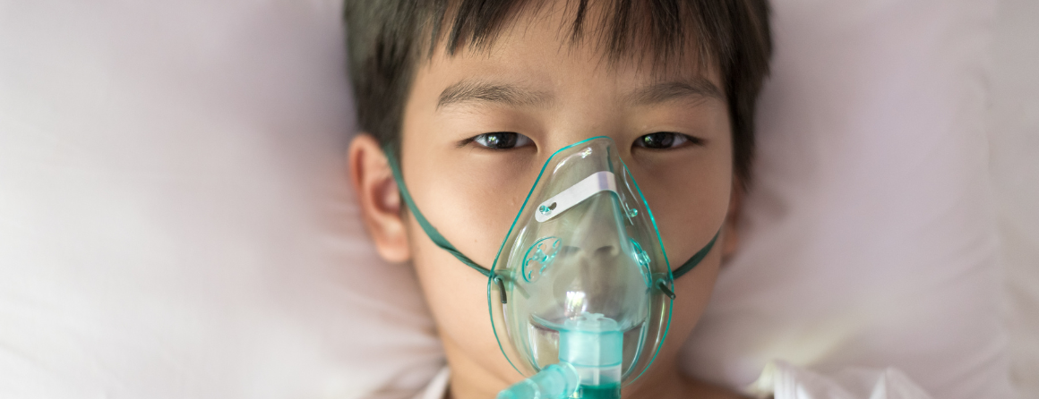 asian boy with face oxygen mask lay on a white bed at hospital