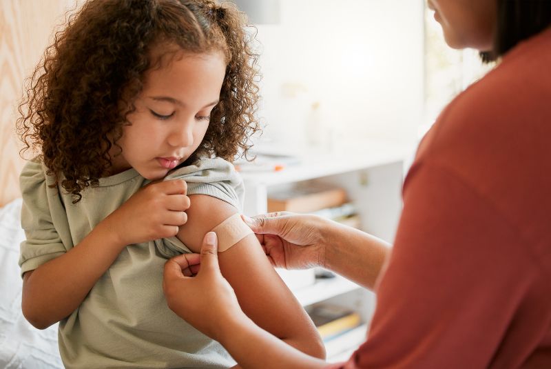 Child having bandaid put on arm after receiving a vaccine