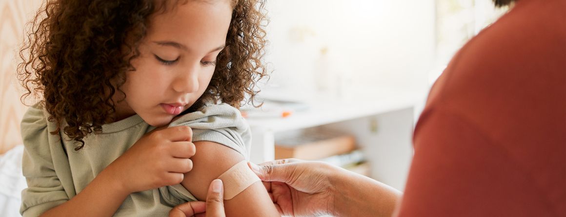 Child having bandaid put on arm after receiving a vaccine