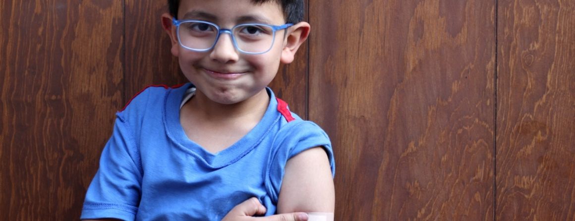A child points to their arm after a COVID-19 vaccine