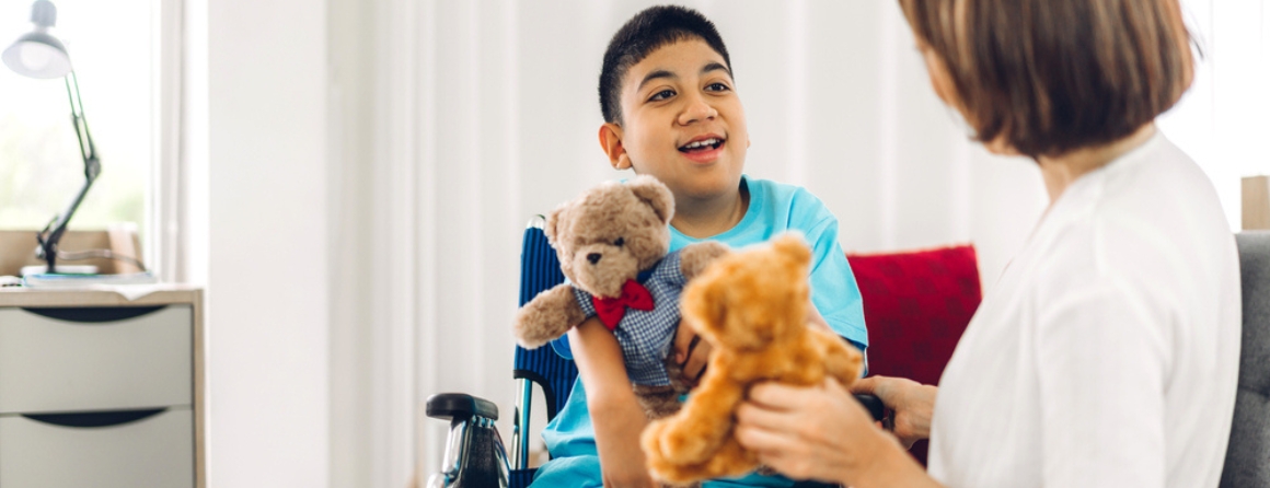 A muscle disease patient is holding a teddy bear