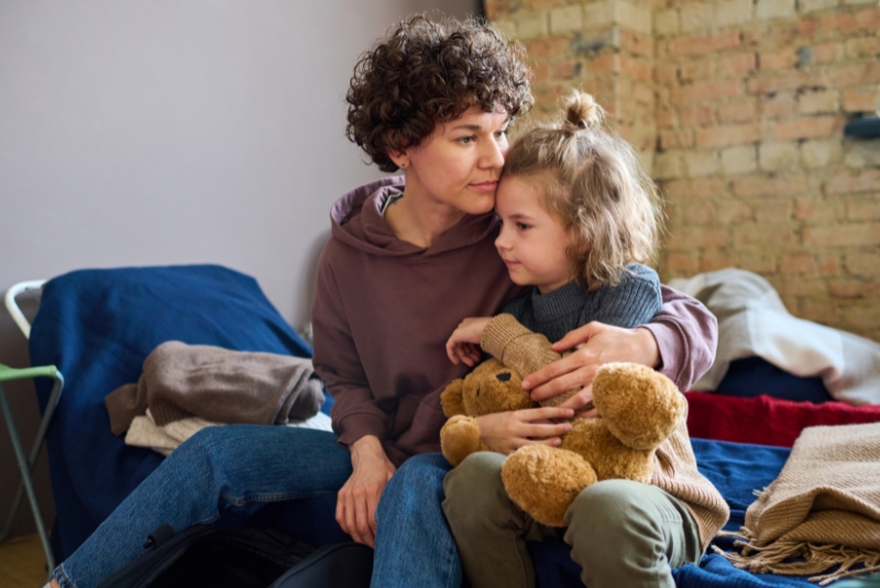 A worried parent with their child and a teddy