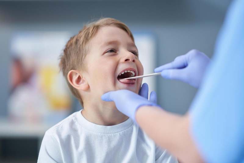 Cheerful boy getting throat examination from doctor 