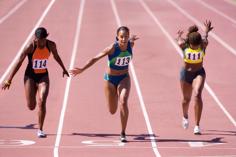 3 female athletes running on a track