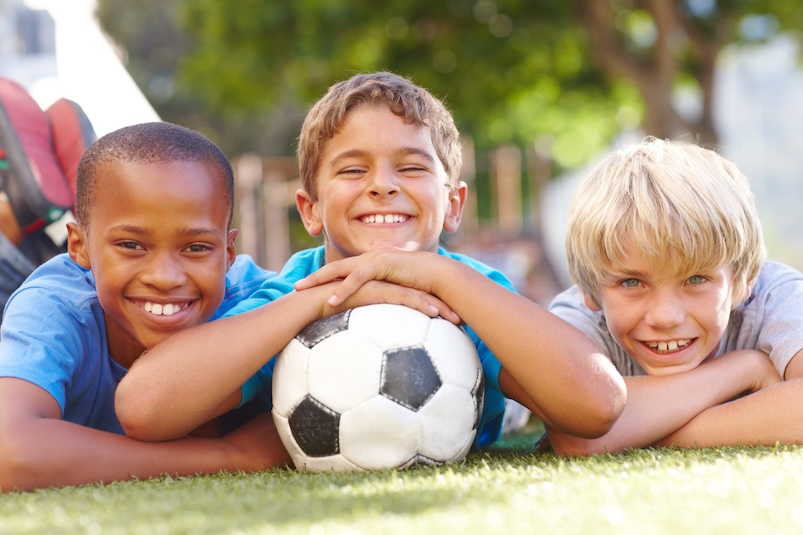 Three boys smiling with a soccer ball
