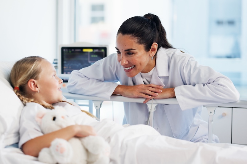 A doctor speaks with a child in a hospital bed