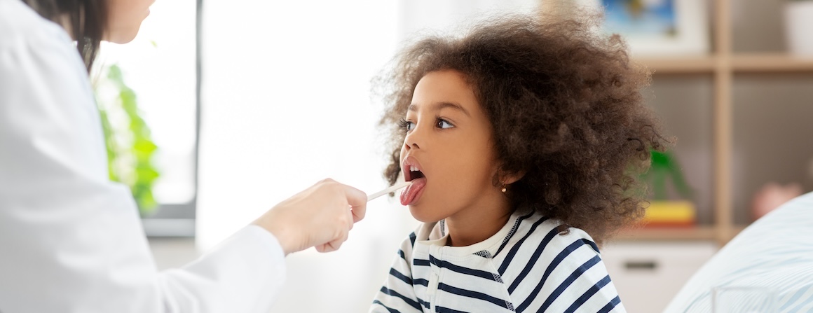 Child has their throat checked by doctor