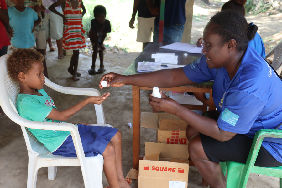 HCC Registered Nurse Delmay Kovo giving a scabies tablet to 7 yr old 