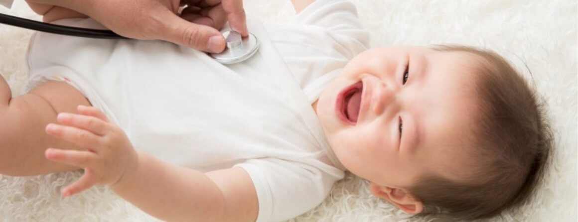 Person using a stethoscope on the chest of a laughing infant.