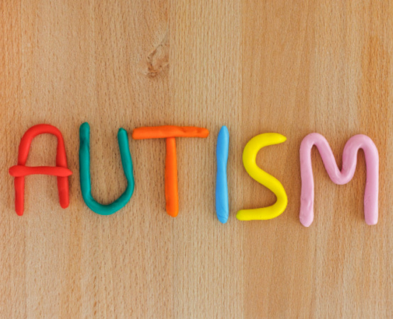 Word 'autism' spelled out with colourful plasticine on wooden background