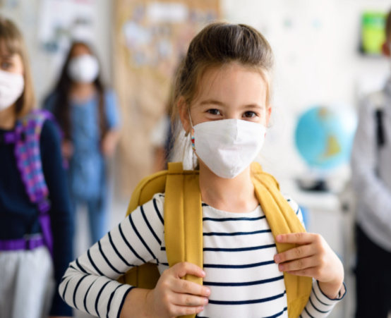 Little girl with school bag wearing a COVID-19 face mask