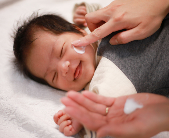 Parent rubbing barrier cream on baby
