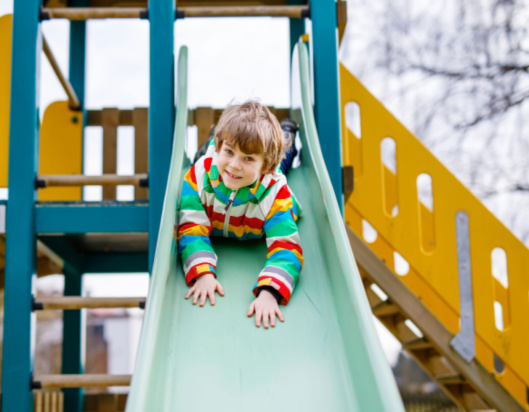 Boy in colourful jacket playing on a slide
