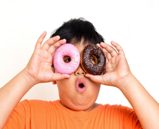 Little boy holds up doughnuts to his eyes