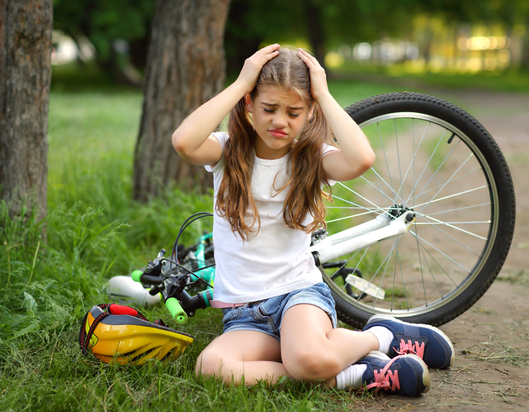 Girl holding head after falling off bike