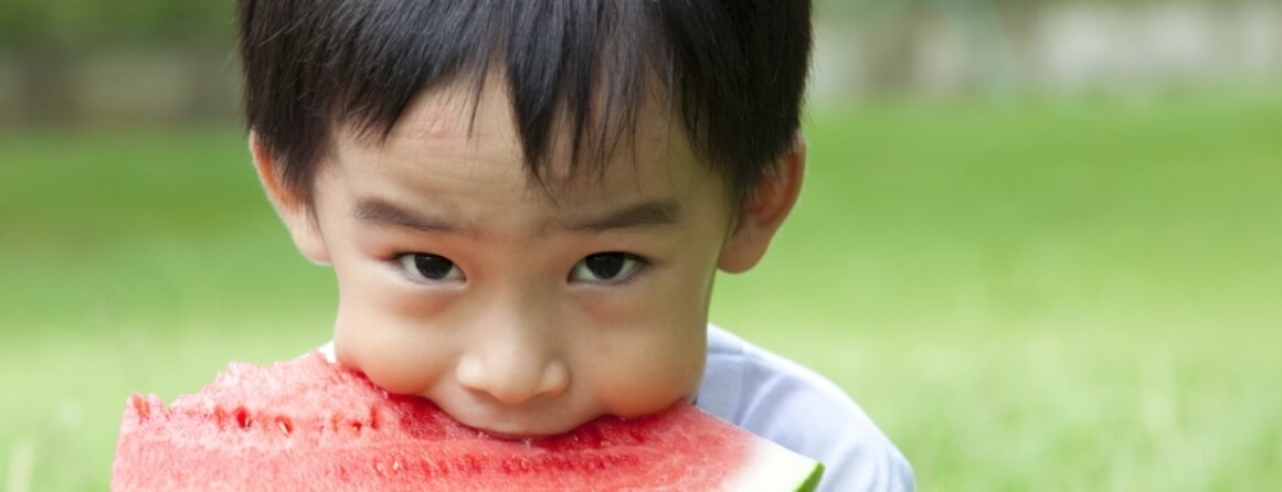 Young boy eating a slice of watermelon.