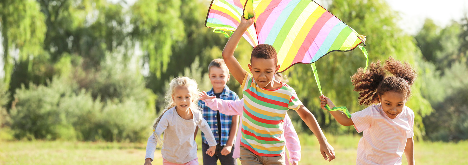 Group of kids running with a rainbow kite