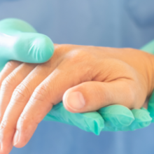 Hand in medical glove holding another hand