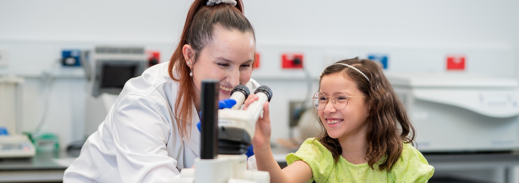 Researcher and child looking through microscope