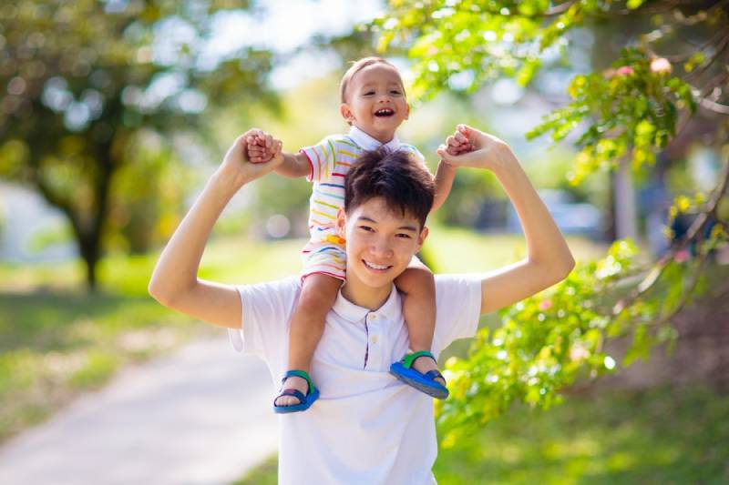 child on shoulders of sibling