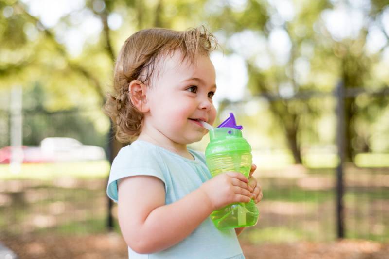 toddler in park on hot day sipping out of water bottle