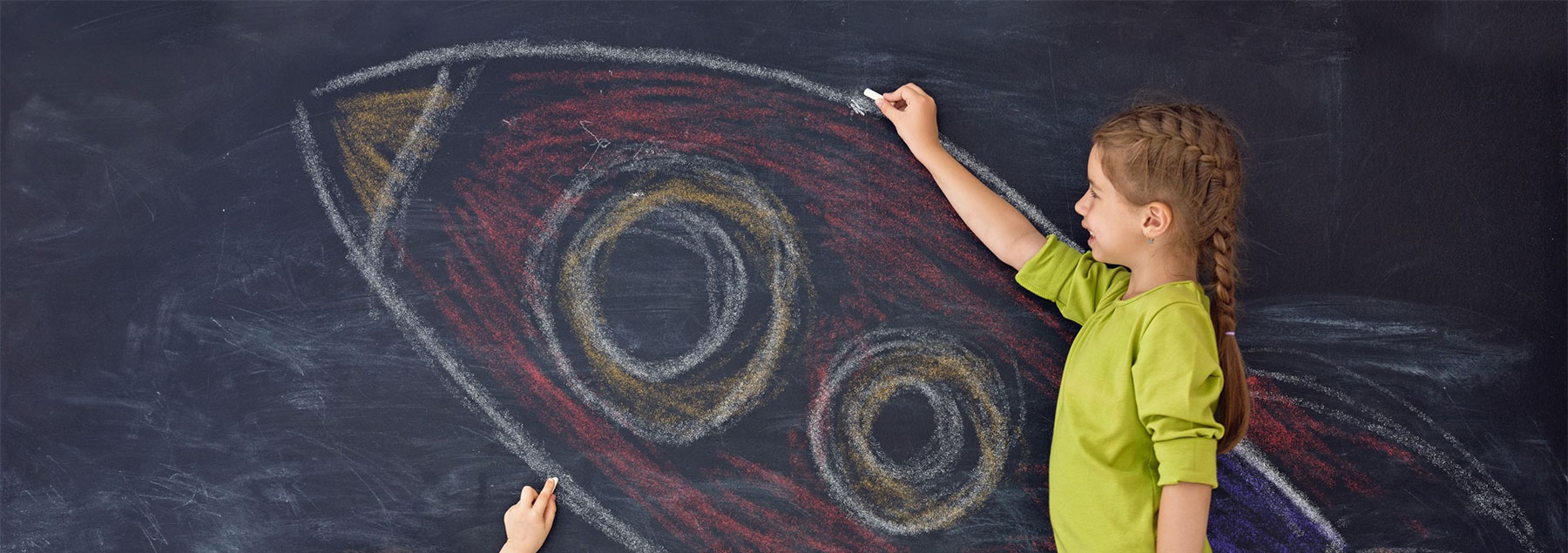 Child drawing a rocket on a blackboard