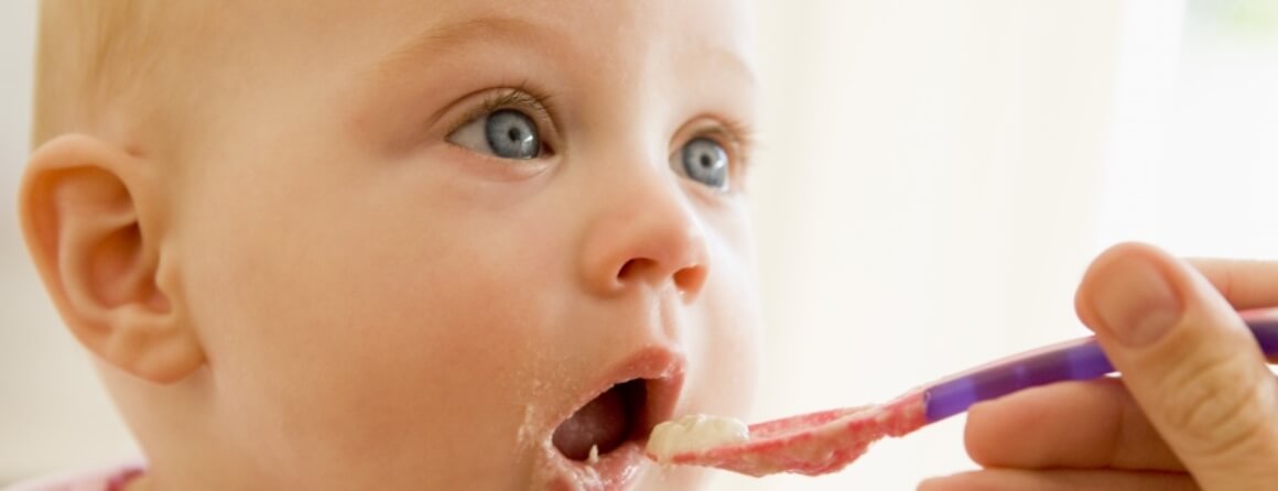 Infant being fed spoonful of food.