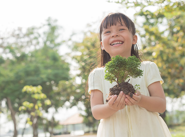 smiling girl holding bonsai tree